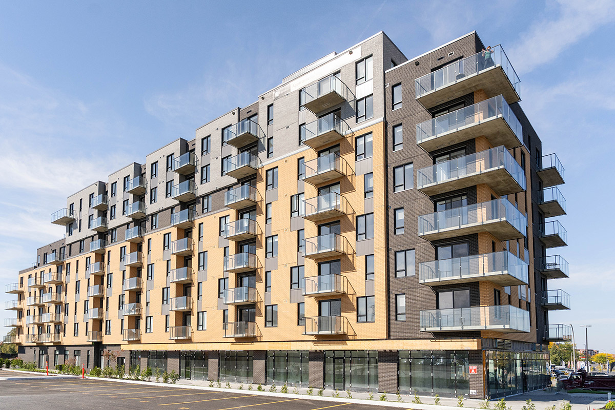 Immeuble résidentiel moderne de 7 étages au 17, rue Hyman à Dollard-des-Ormeaux, avec balcons privés, grandes fenêtres et rez-de-chaussée commercial vitré.